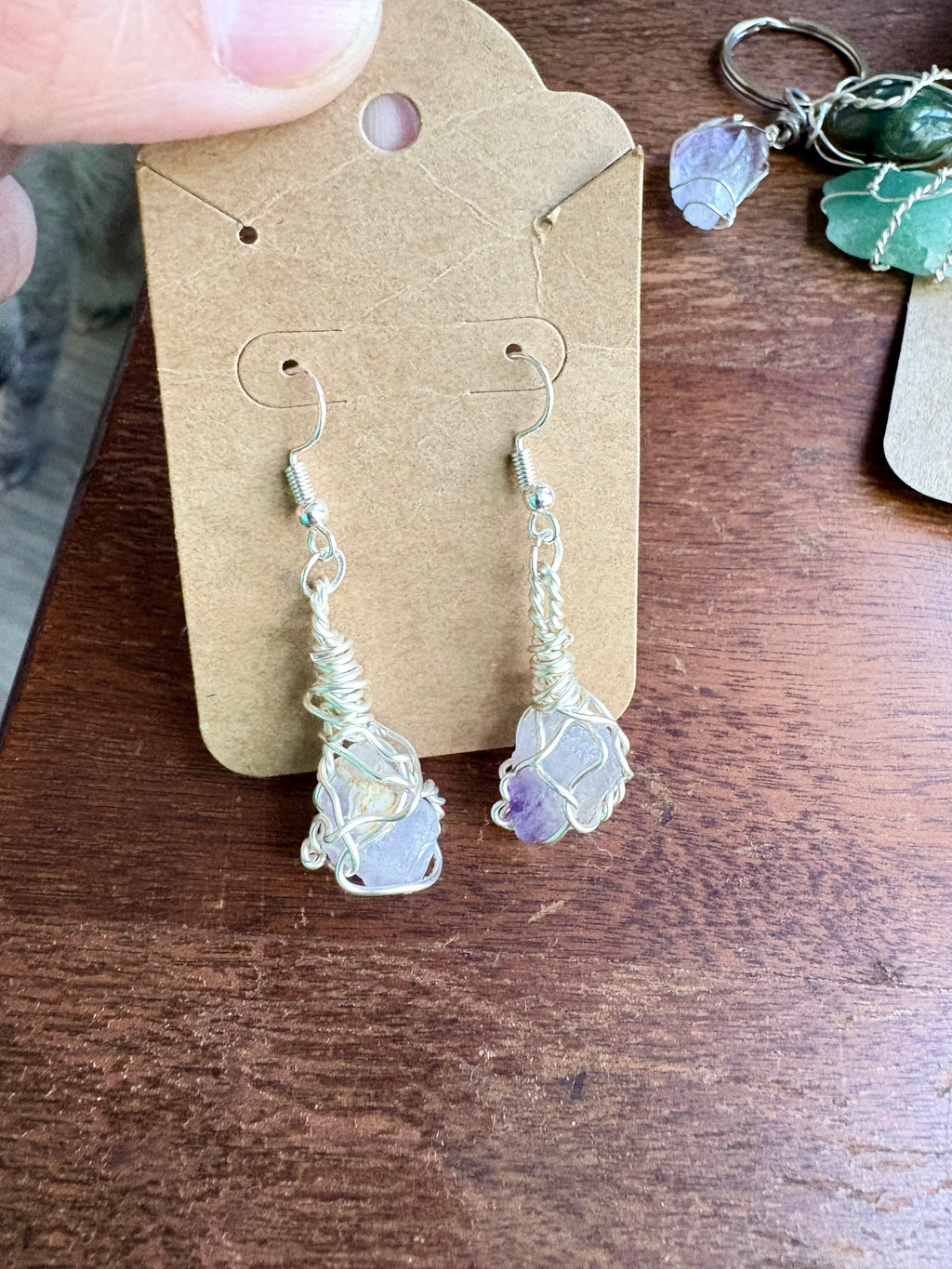 A pair of handmade dangle earrings with purple stones wrapped in silver wire