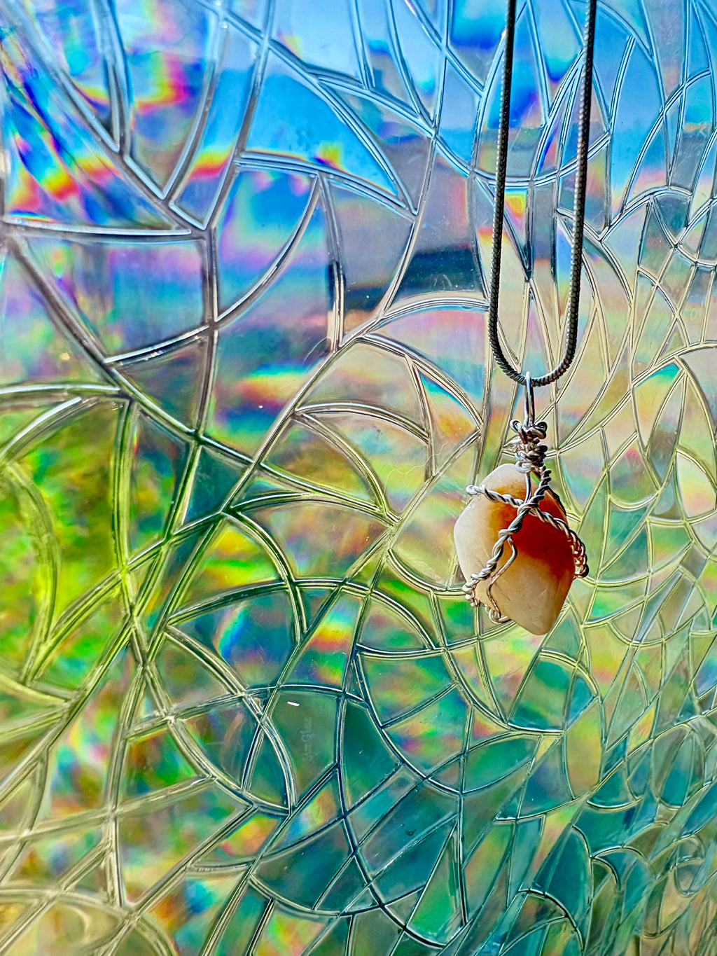 Necklace with a pendant against a colorful stained glass window background