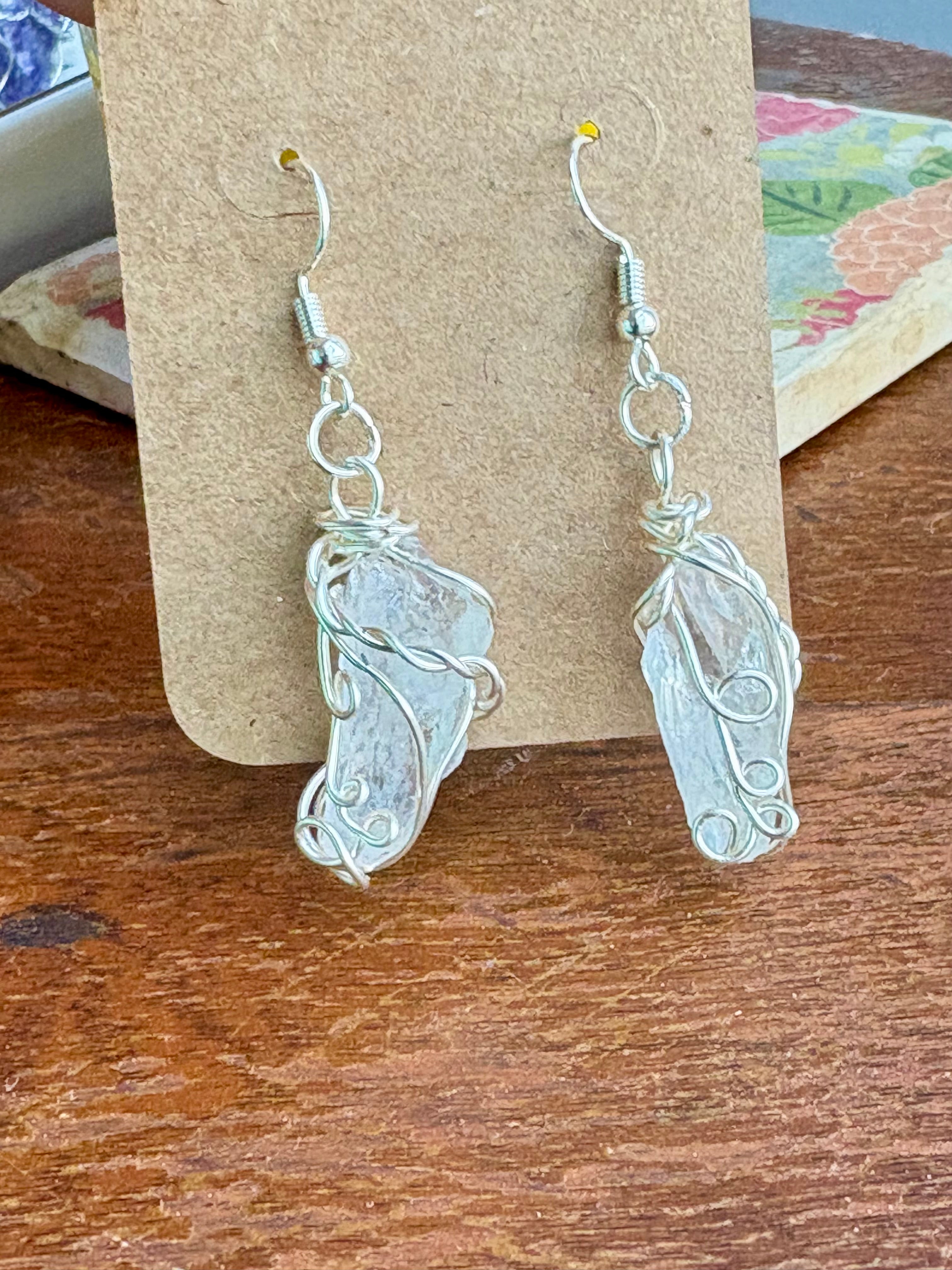 A pair of handmade silver dangle earrings.  Swirl and twist  design against clear crystals.