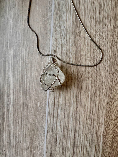 A rounded, raw quartz stone wrapped in copper wire
