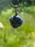 Blue stone pendant on a chain against a blurred green background