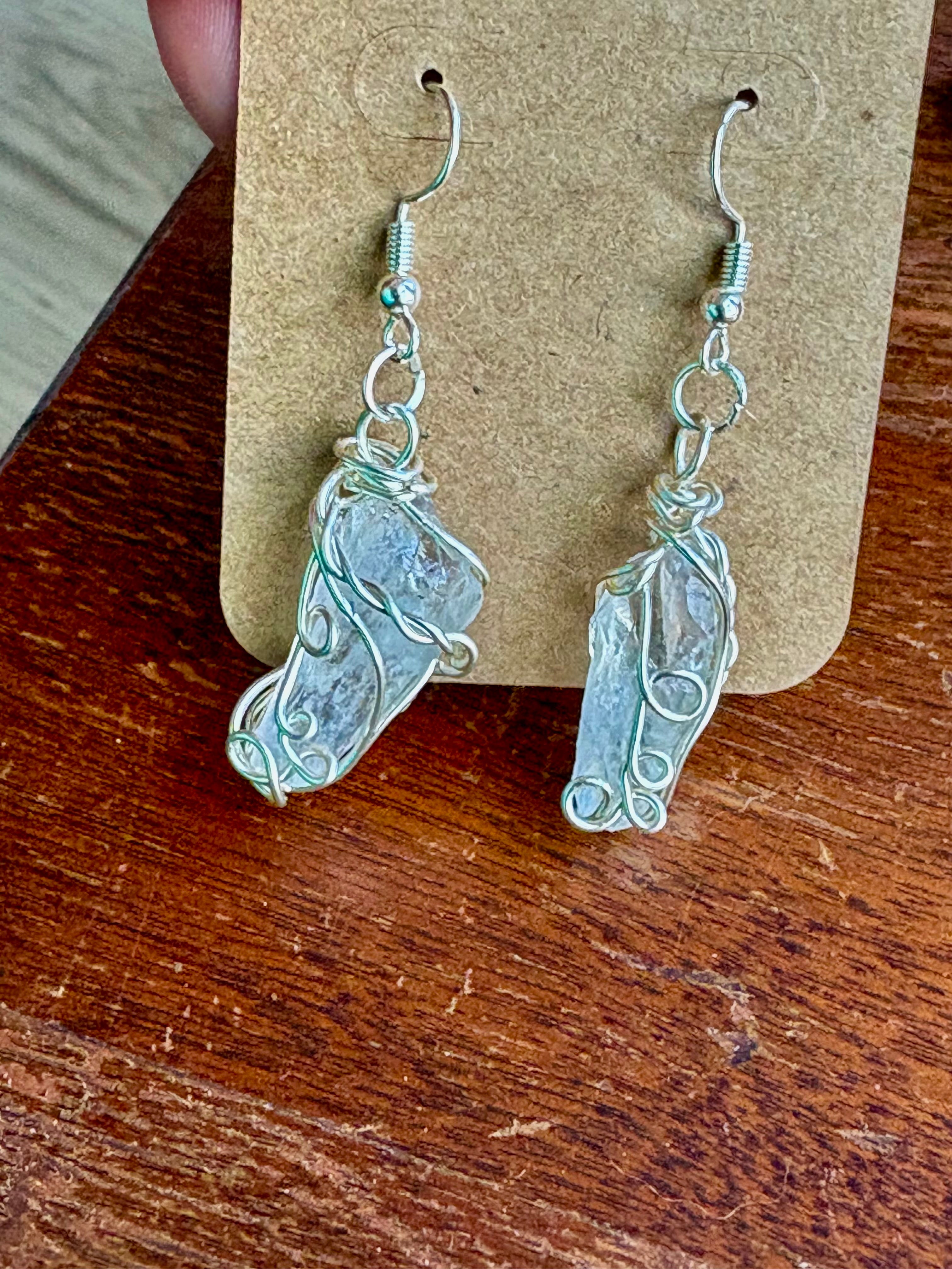 A pair of handmade silver wire earrings with irregular, textured stone pendants